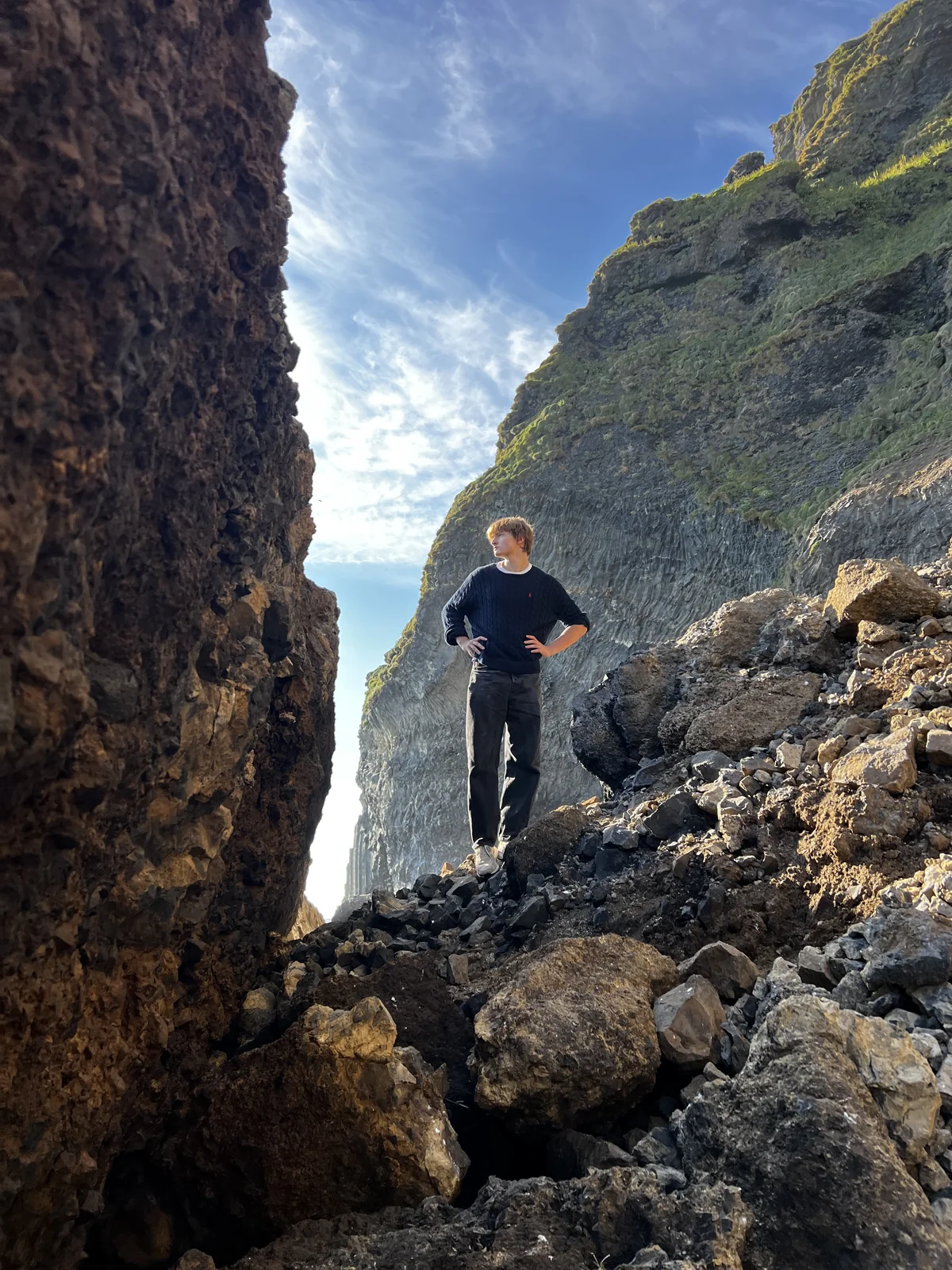 Georgii Demkin standing among rocks between tall cliffs in Iceland