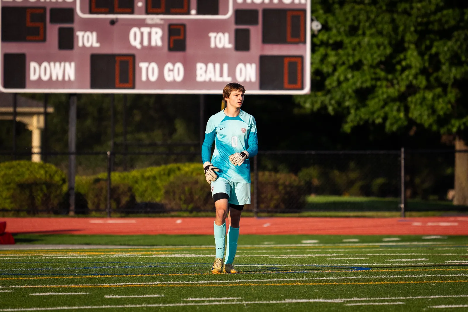 Georgii Demkin wearing goalkeeper gloves and a turquoise kit on a soccer field